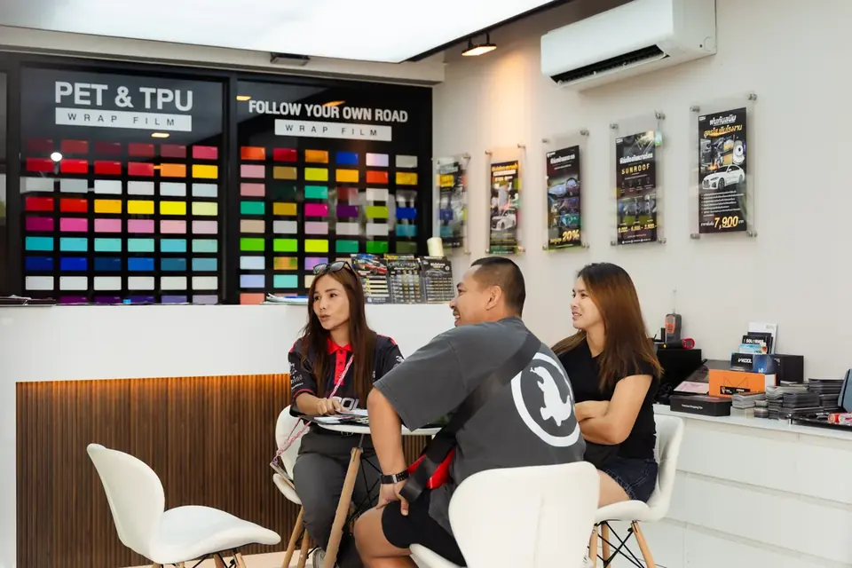 ทีมงานให้คำปรึกษาลูกค้าที่โต๊ะรับรอง หน้าผนังตัวอย่างฟิล์ม PET & TPU